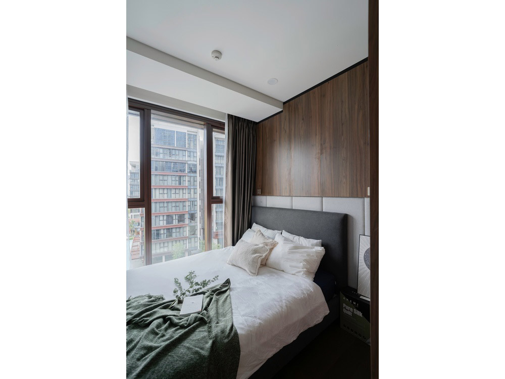 ID 2256 second bedroom with large window dressed bed and wood accent wall.